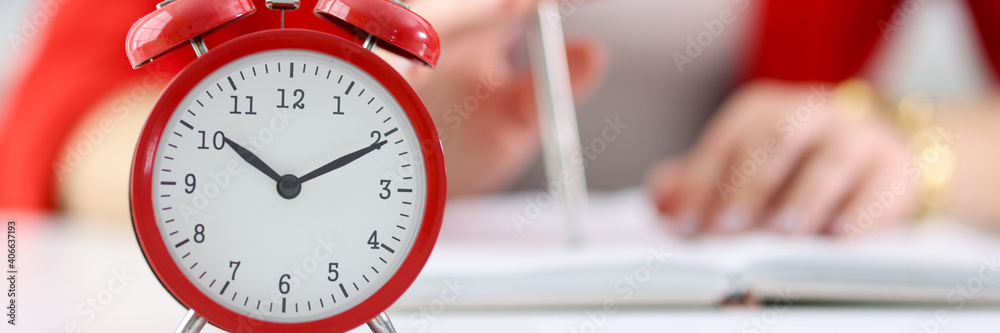 Against the background of businesswoman stands red alarm clock. Time management in business concept Against the background of businesswoman stands red alarm clock. Time management in business concept