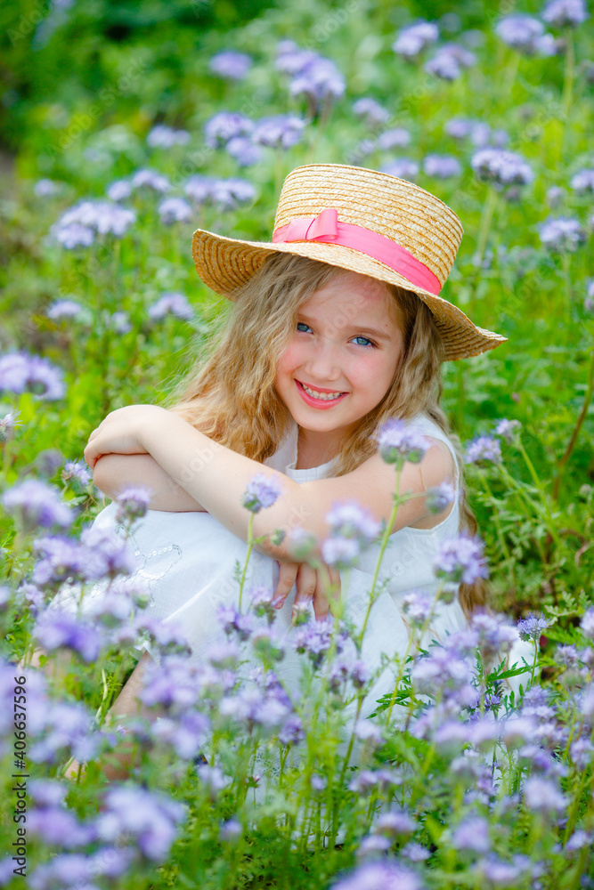 little girl in a straw hat in a purple field in summer