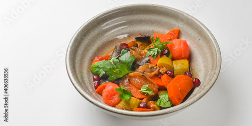 Baked vegetable salad in a cermaic bowl over white background. Delicious healthy autumn or winter salad.
