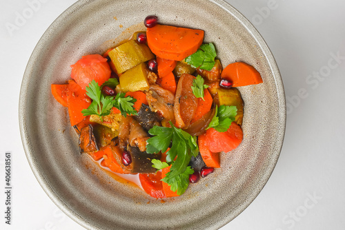 Baked vegetable salad in a cermaic bowl over white background. Delicious healthy autumn or winter salad. photo