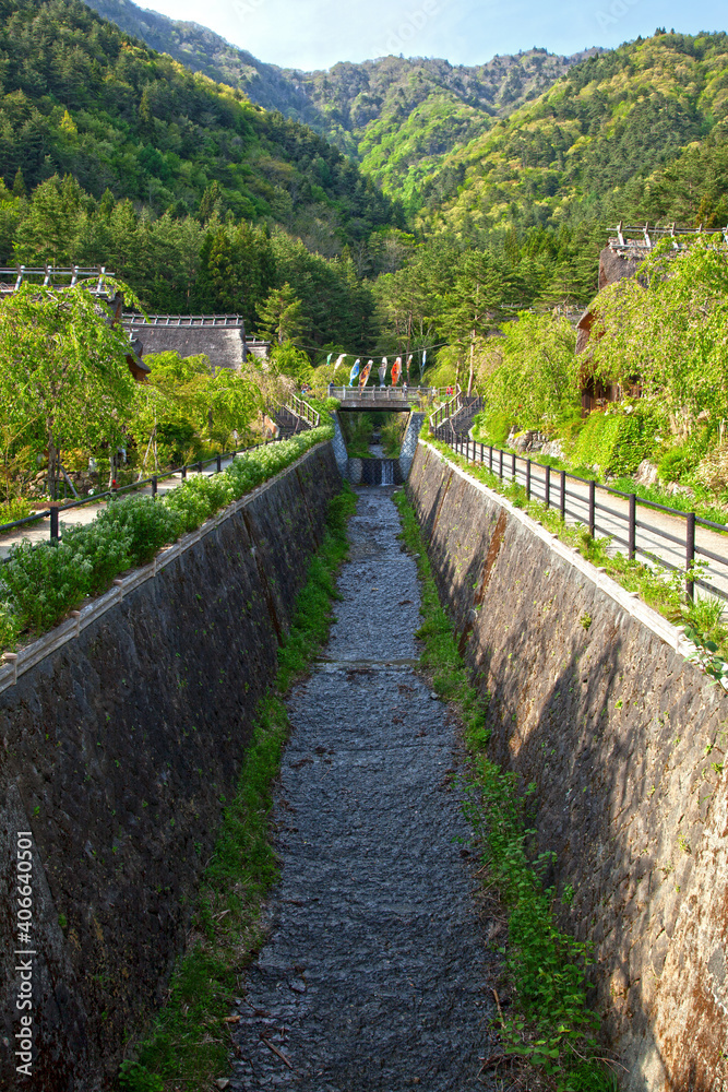 A stream and hills where the traditional village of Saiko Iyashi no Sato Nemba is located near Mount Fuji in Japan.