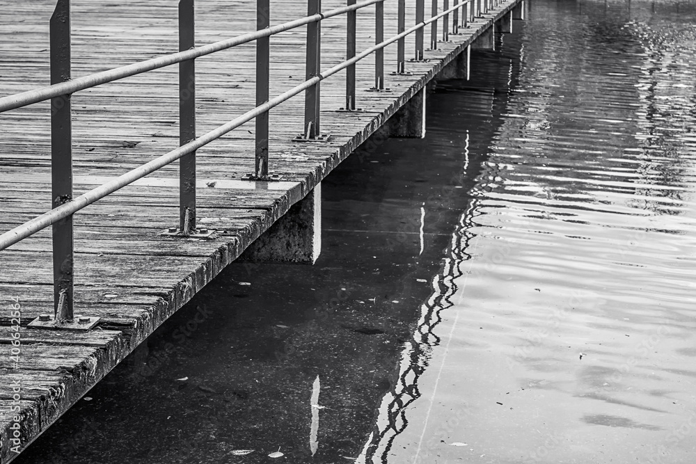 Obraz premium Railing of the walkway of a jetty over the water. Black and white.