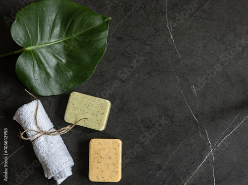 Spa composition with towel, handmade soap and tropical leaf top view.