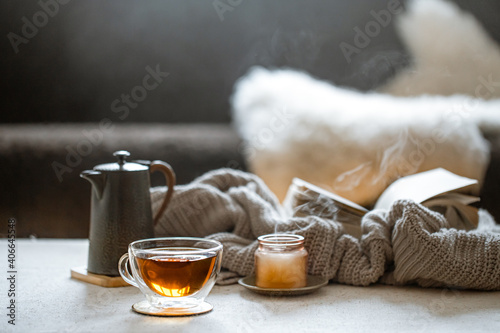 Cozy home composition with cup of tea, kettle and candle on blurred background ccopy space. photo