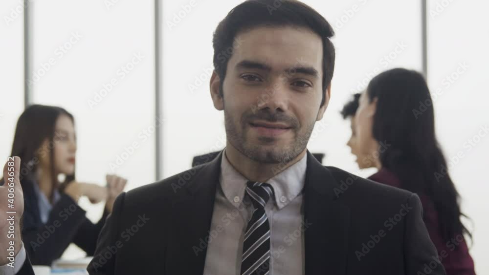 Conference call concept. Businessman talking to camera while team having meeting. He report business project with team. Conference call concept. Businessman talking to camera while team having meeting. He report business project with team.