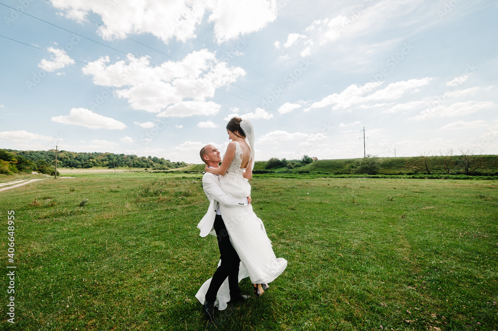 The first meeting is newlyweds in a green park outdoors. Bride hugging groom, surprise in nature. Happy wedding day of marriage. The first meeting is newlyweds in a green park outdoors. Bride hugging groom, surprise in nature. Happy wedding day of marriage.