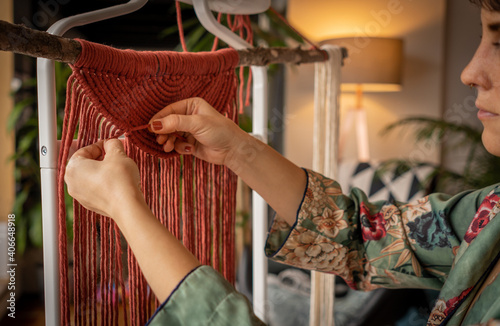 A woman working on a macrame wall hanger at home during the lock down