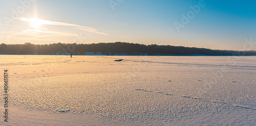 Landscape of a frozen lake in winter time during a golden hour sunset