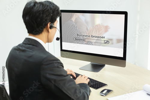 Rear view of businessman sitting at computer, typing searching browsing internet data information, internet digital marketing concept.