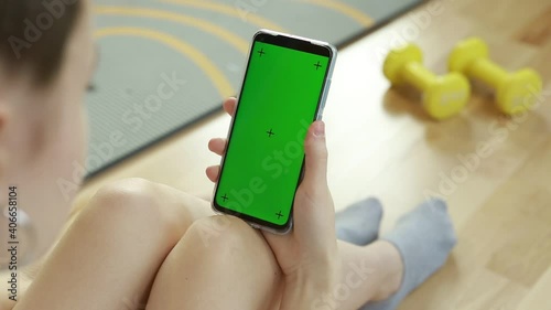 Phone with Green Screen and Chroma Key. Teenage girl prepares for sports online video.
