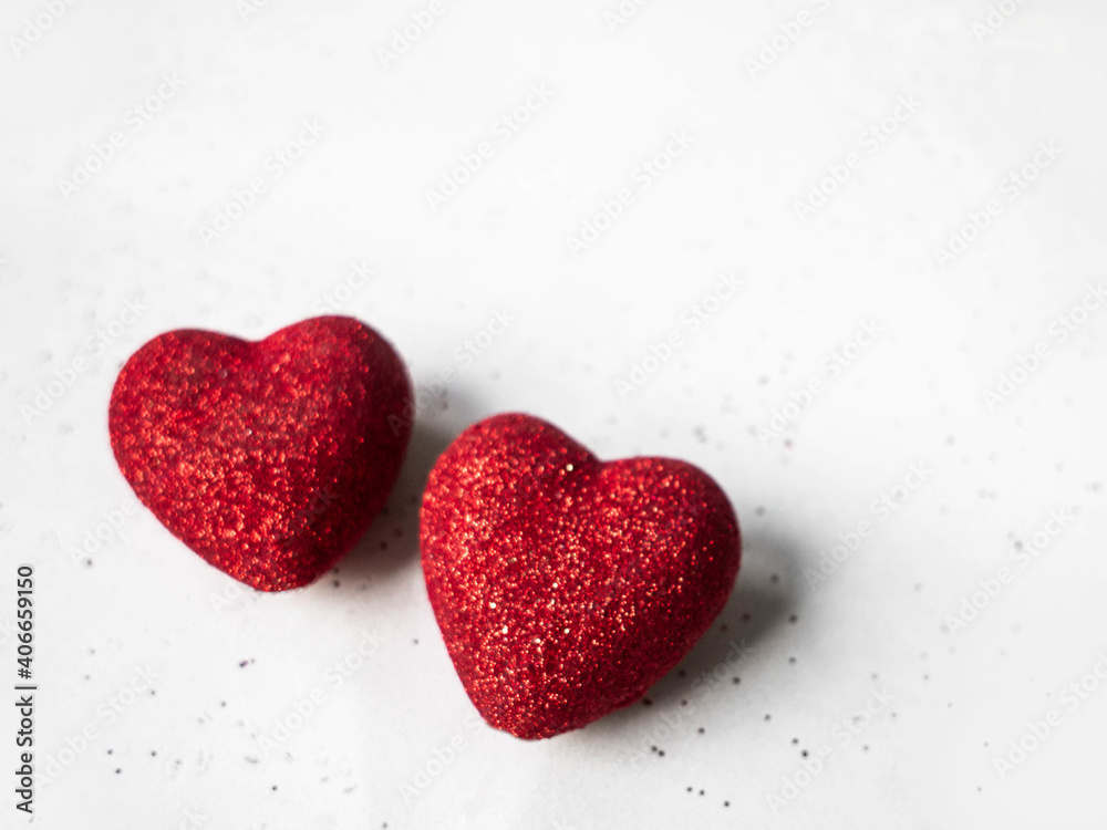 Two red shiny hearts on a gray background.