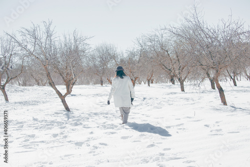 Panoramic and back view photography of unrecognizable adult woman walking in winter forest. Snowy nature landscape with footprints in the snow. Activity relax on fresh air concept.