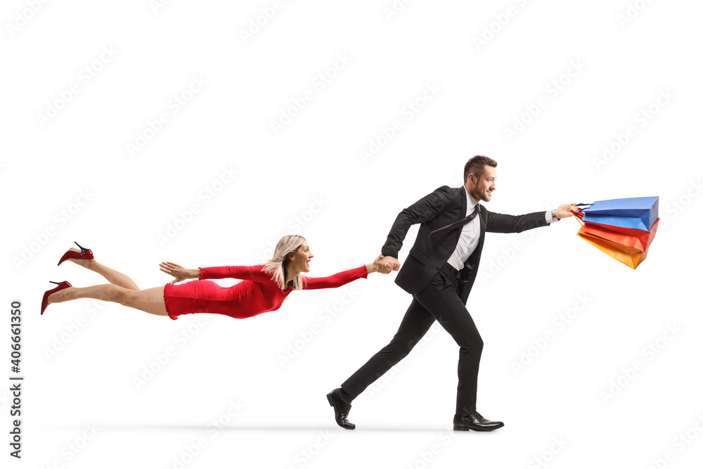 Man holding shopping bags and running with a flying woman in a red dress