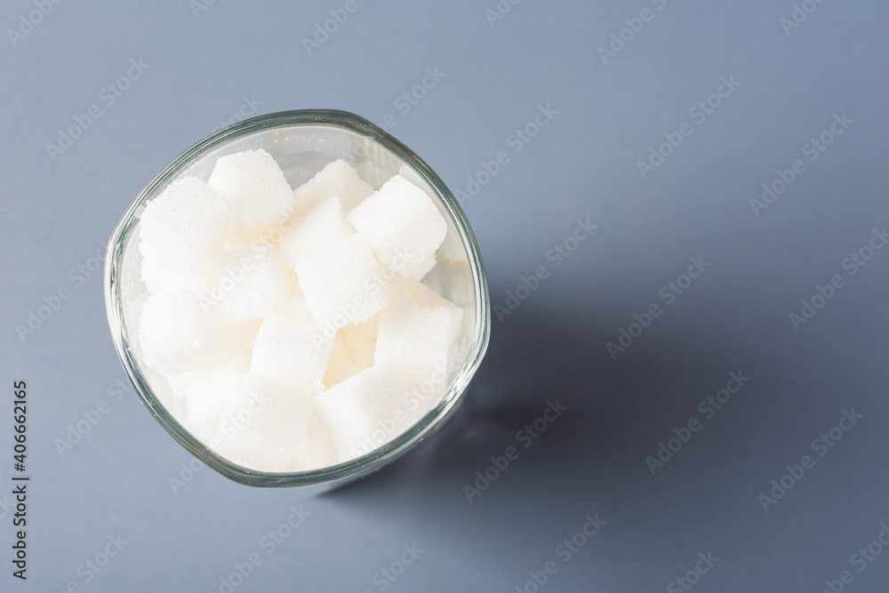 Top view glass full of white sugar cube sweet food ingredient, studio shot isolated on gray background, health high blood risk of diabetes and calorie intake concept and unhealthy drink Top view glass full of white sugar cube sweet food ingredient, studio shot isolated on gray background, health high blood risk of diabetes and calorie intake concept and unhealthy drink