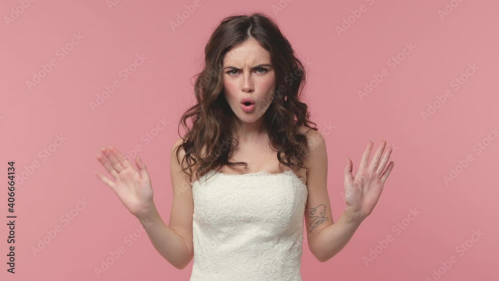 Displeased bride young brunette woman 20s in beautiful white wedding dress posing isolated on pink pastel color background studio. Wedding concept. Say no holding folded crossed hands in stop gesture
