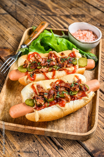 Hot dogs with fried bacon, onion and pickled cucumbers. wooden background. Top view