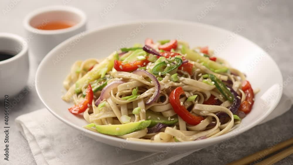 Noodles with vegetables on a deep white plate sprinkled with sesame seeds Noodles with vegetables on a deep white plate sprinkled with sesame seeds