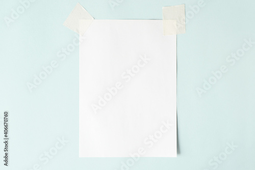 White sheet on scotch tape, layout. Blank sheet of paper on a pastel blue background, copy space