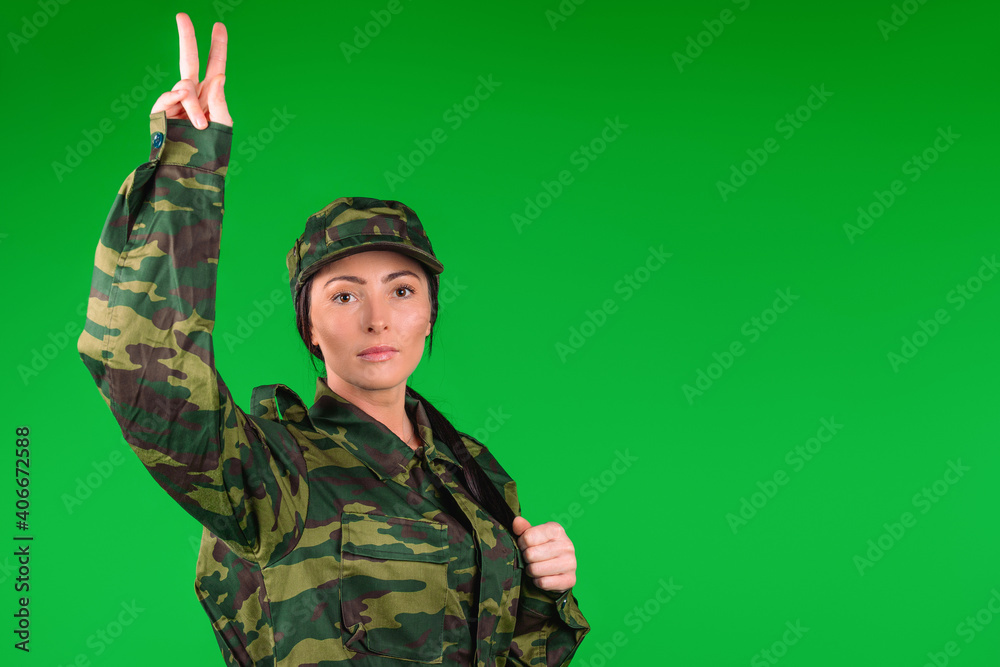 Military woman showing victory and peace sign on green background with blank side space for your advertisemeent Military woman showing victory and peace sign on green background with blank side space for your advertisemeent