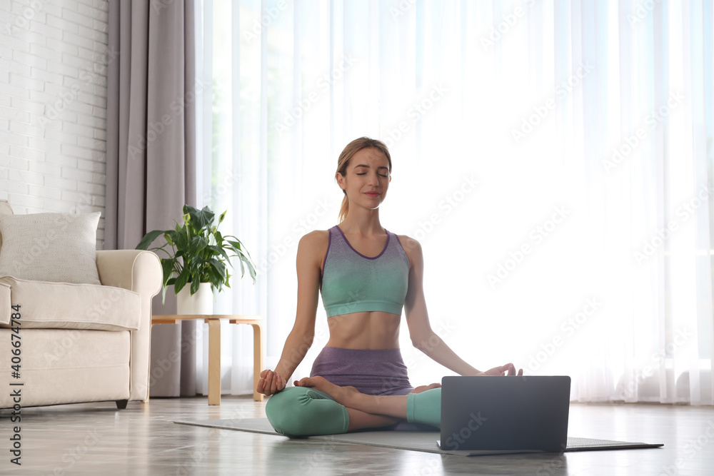 Woman having online video class via laptop at home. Distance yoga course during coronavirus pandemic Woman having online video class via laptop at home. Distance yoga course during coronavirus pandemic