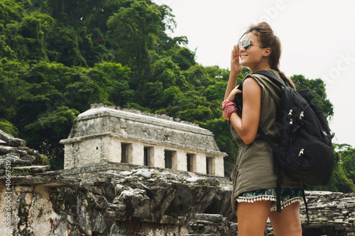 Woman with a backpack beside ancient Mayan ruins