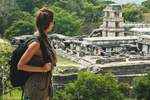 Woman with a backpack beside ancient Mayan ruins photo