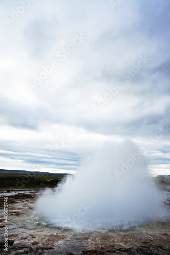 The Great Geysir, geyser in southwestern Iceland, Haukadalur valley, Geyser splashing out of the ground against the background of a cloudy sky, abstract vertical background with water