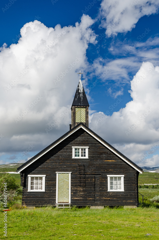 Small black wooden church on green hills Norway tundra