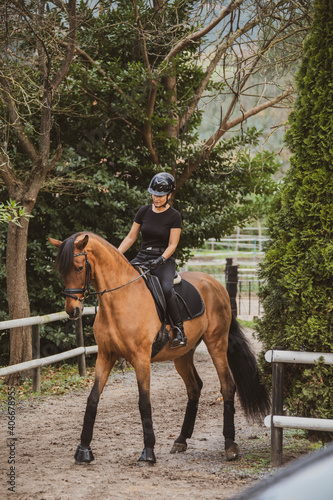 woman riding her brown horse with black mane dressed in black with a helmet