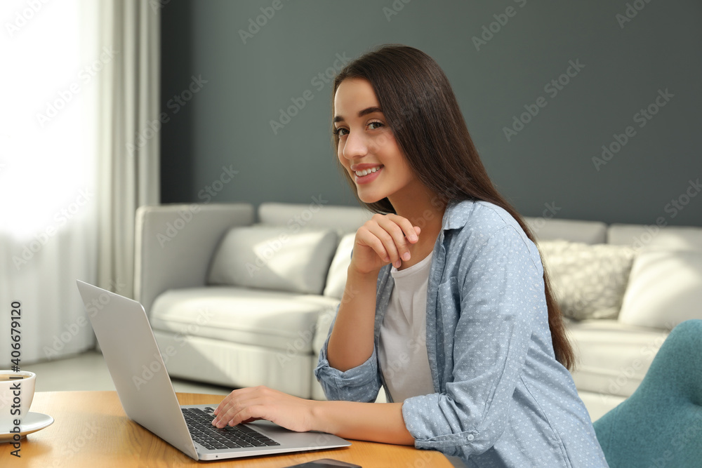 Fototapeta premium Young woman using laptop for search at wooden table in living room