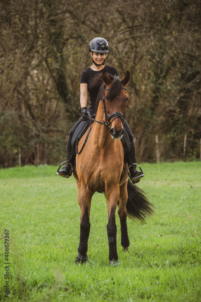 woman riding her brown horse with black mane dressed in black with a helmet woman riding her brown horse with black mane dressed in black with a helmet