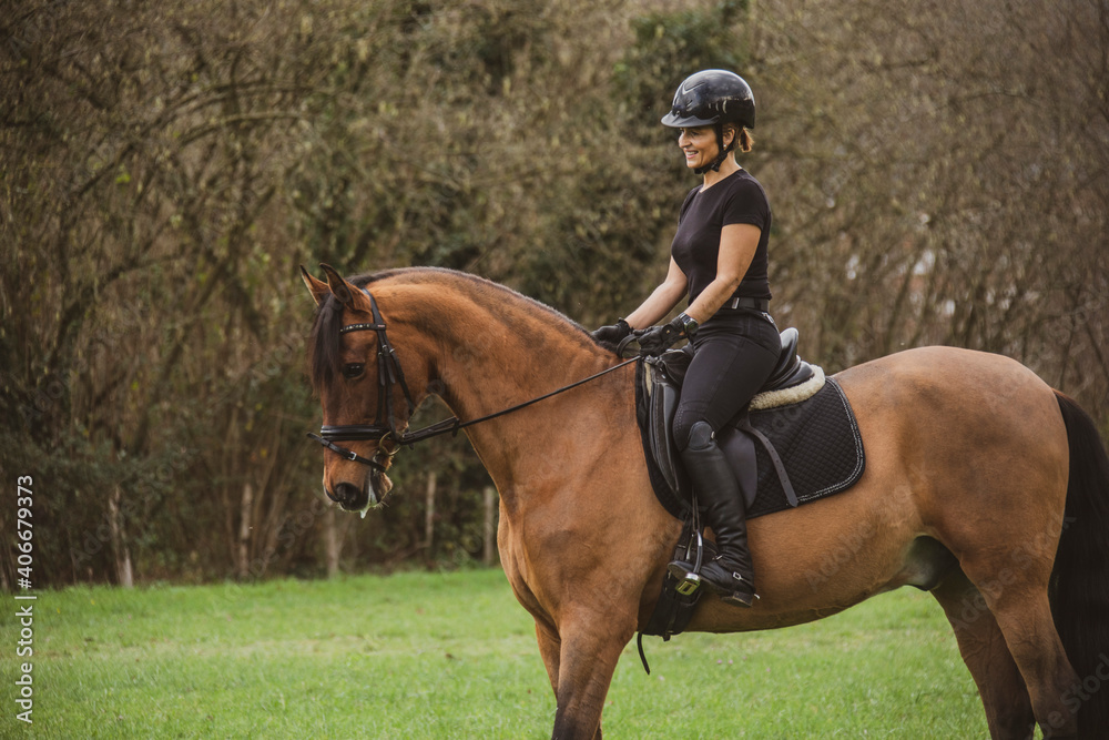 woman riding her brown horse with black mane dressed in black with a helmet woman riding her brown horse with black mane dressed in black with a helmet