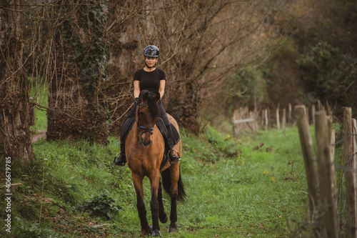 woman riding her brown horse with black mane dressed in black with a helmet