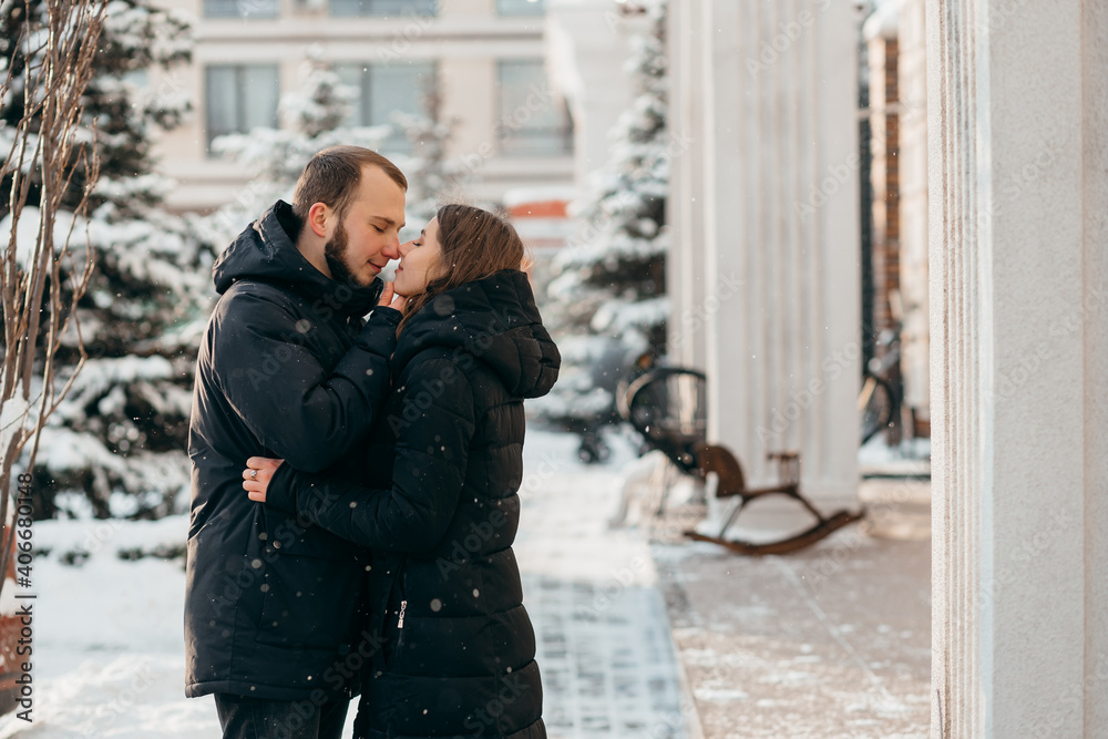 the guy gently kisses the girl against the background of the snowy city