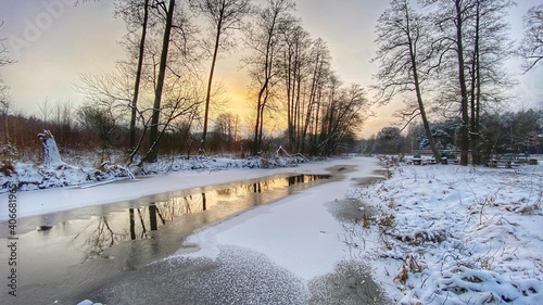 Fototapeta Naklejka Na Ścianę i Meble -  zimowy krajobraz częściowo zamarzniętej rzeki koło Włodawy dużo śniegu niebieskie niebo złota godzina 