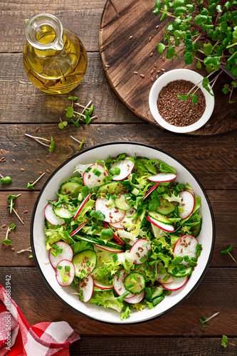 Radish and cucumber salad with fresh green onion in bowl  Top view