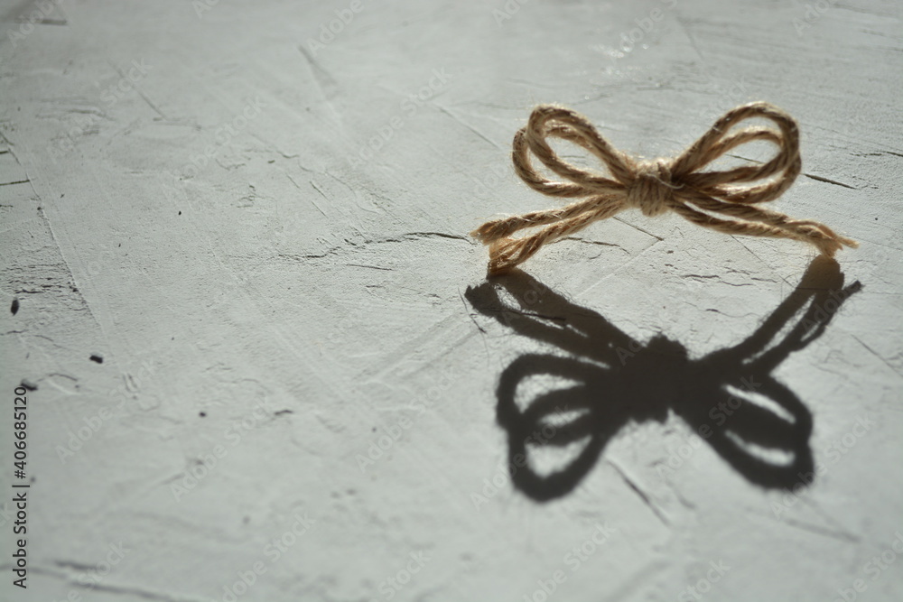 Creative photo of a bow from a string on a gray background with a hard light. Horizontal photography. Copy space
