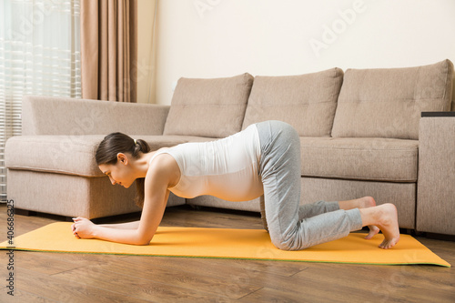Pregnant woman meditating while sitting in yoga position. Meditating on maternity Pregnancy Yoga and Fitness concept at coronavirus time