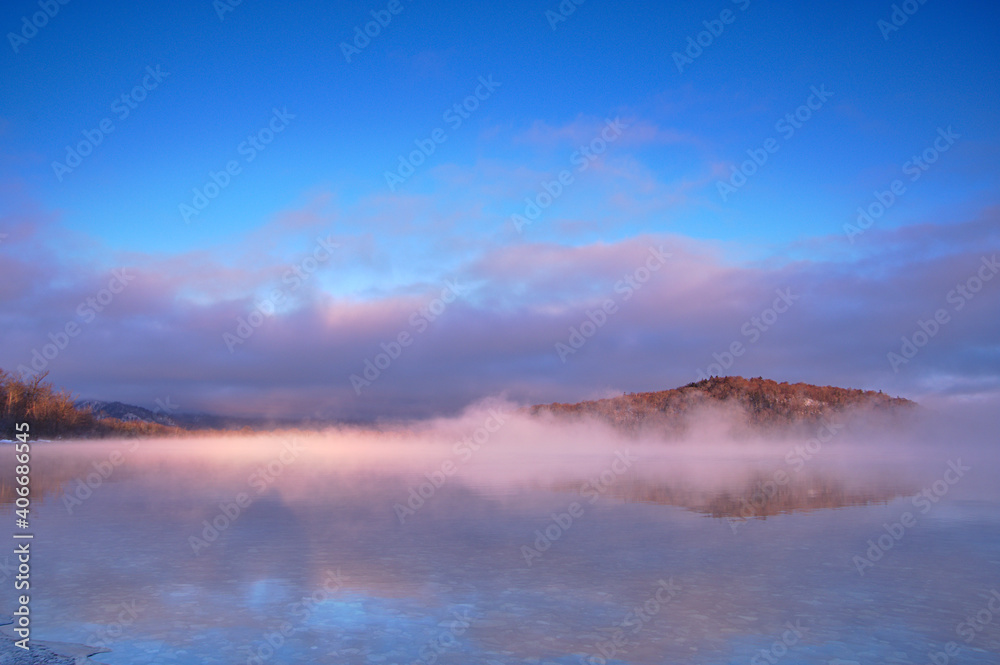 湖面に朝靄の漂う早朝の湖。氷点下の朝の屈斜路湖。阿寒摩周国立公園。北海道、日本。