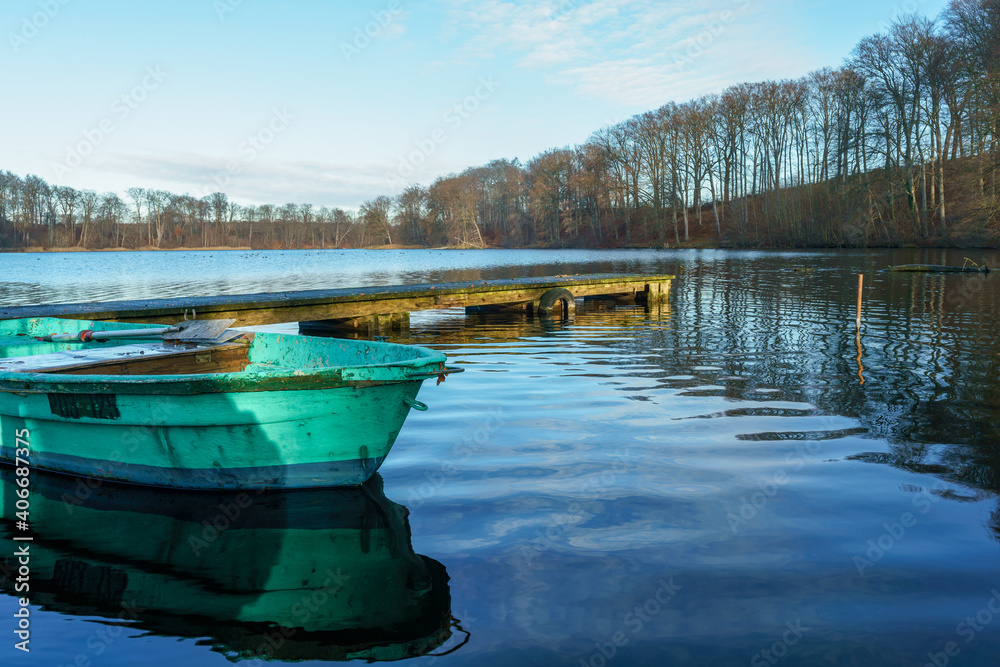 Idyllic scene with a green rowing boat on a sunny winter day at Huwenowsee lake Idyllic scene with a green rowing boat on a sunny winter day at Huwenowsee lake