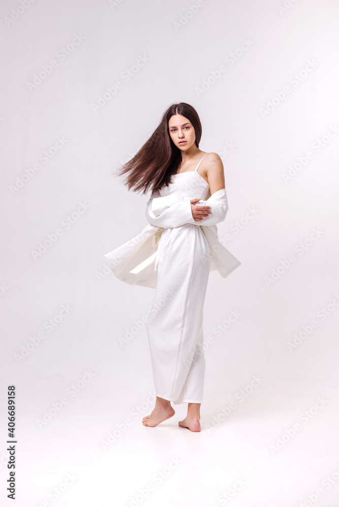 Fashion portrait of a beautiful brunette in white eco clothes on a white background Fashion portrait of a beautiful brunette in white eco clothes on a white background