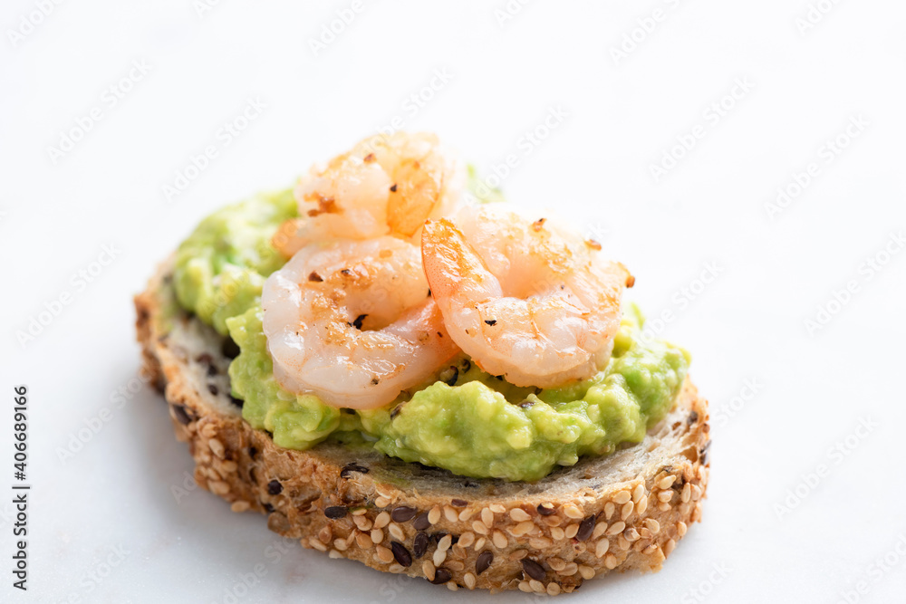 Appetizer toast or bruschetta with avocado cream and shrimps isolated on white marble background Appetizer toast or bruschetta with avocado cream and shrimps isolated on white marble background