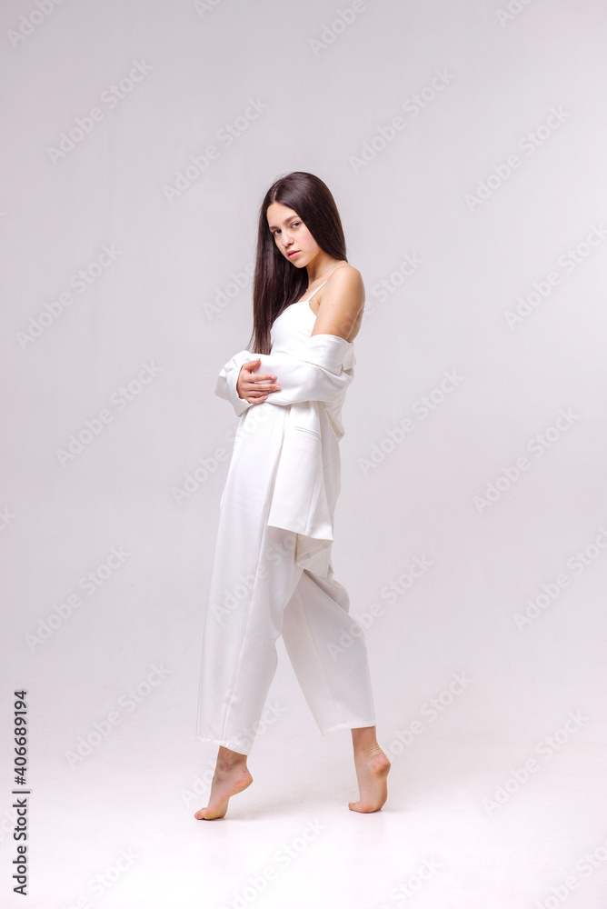 Fashion portrait of a beautiful brunette in white eco clothes on a white background Fashion portrait of a beautiful brunette in white eco clothes on a white background