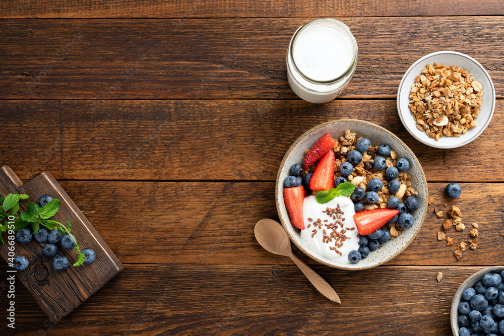 Granola bowl with berries and greek yogurt on a rustic wooden table background, top view - obrazy, fototapety, plakaty 