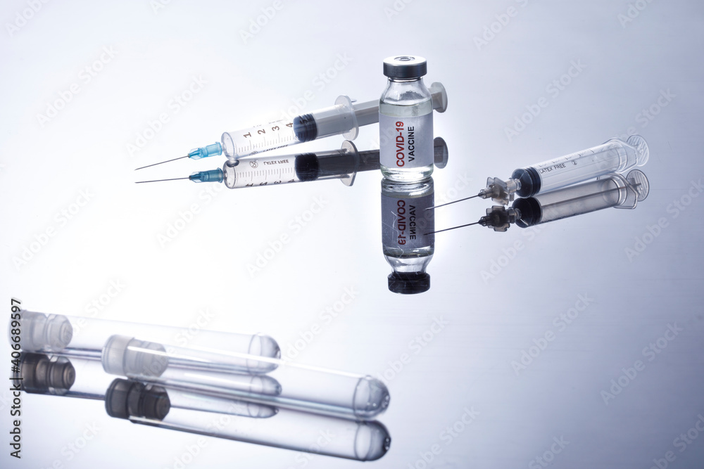 Flacone di vaccino contro il coronavirus con Siringhe , isolati su sfondo bianco riflettente Flacone di vaccino contro il coronavirus con Siringhe , isolati su sfondo bianco riflettente