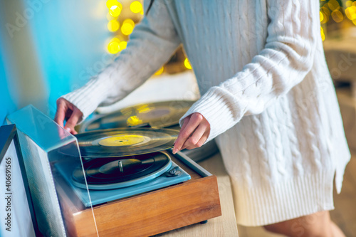 Woman in white clothes putting a record on