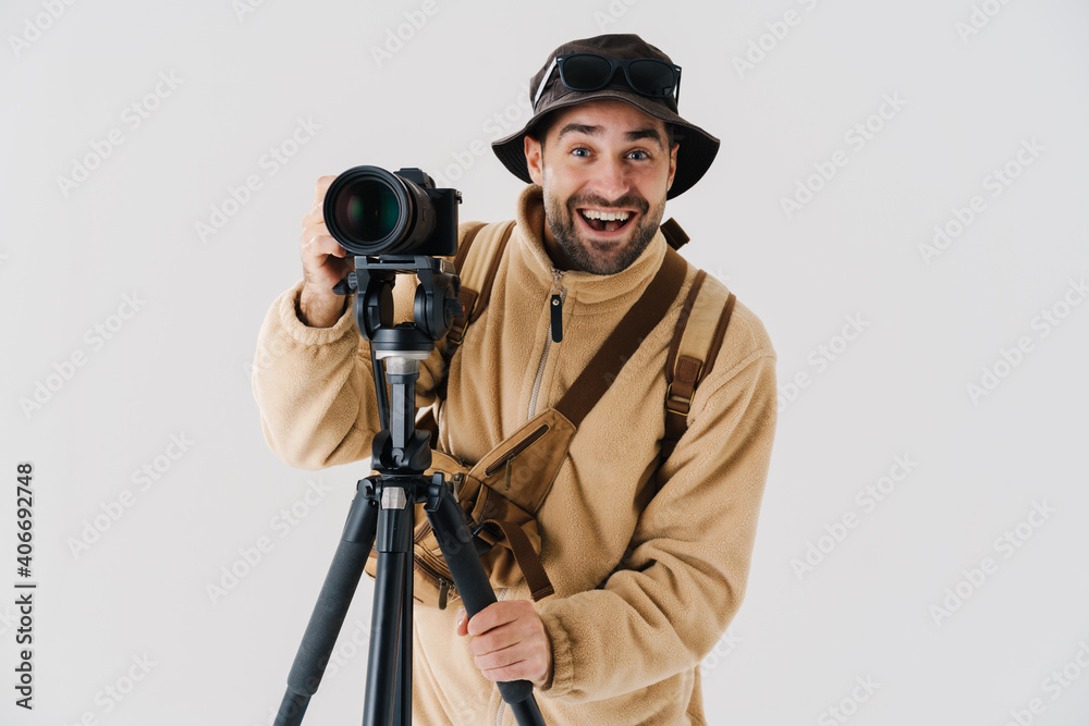 Joyful young photographer posing with digital camera and tripod