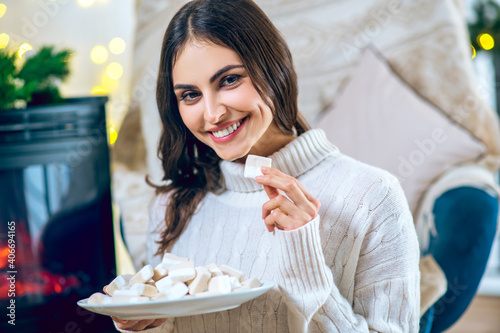 Woman in white clothes eating marshmallow and smiling