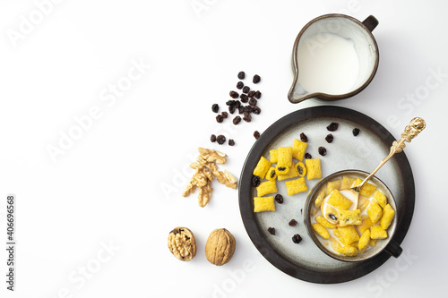 walnuts and raisins lie on the table next to milk and cornflakes in a cup
