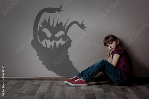 Shadow of monster on wall and scared little girl in room photo